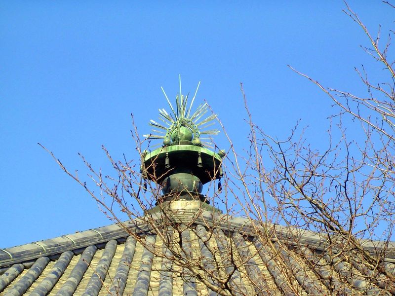 The roof ornament consists of a base, a "sacred jewel" sparkling in the suien or "flame" style, and a summit flask suggesting that the build