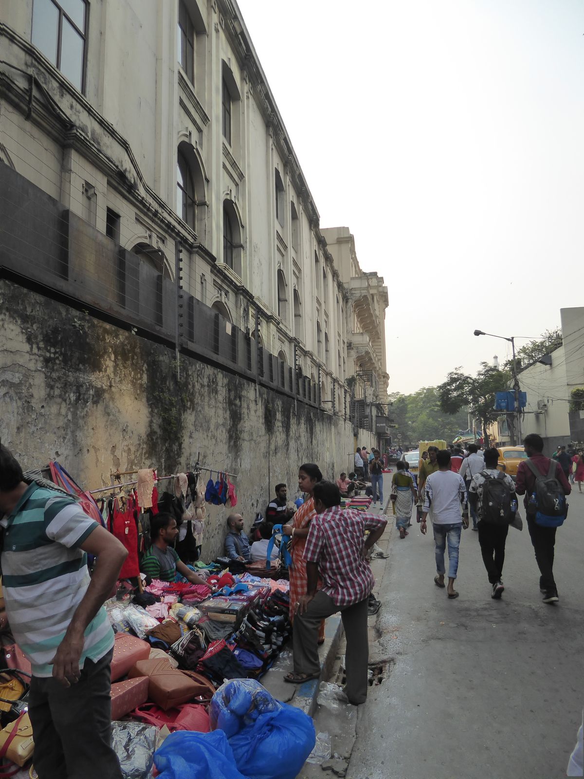 Chowringhee, and the greenery of the maidan, is up ahead. We'se stepped off the thoroughfare and are on the north side of the Oberoi, its wa