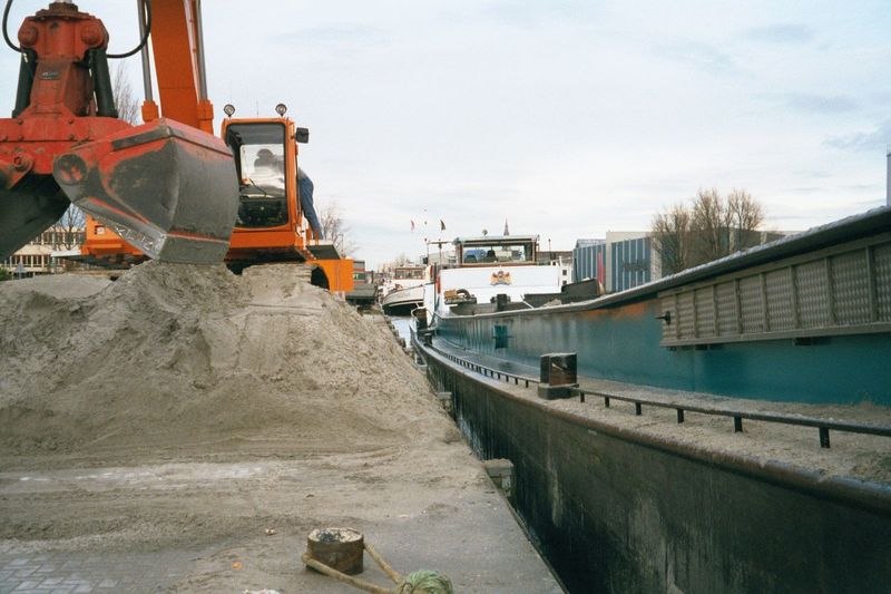 An obvious candidate for water transport. The sand is being unloaded from the barge and banked for pickup by trucks.