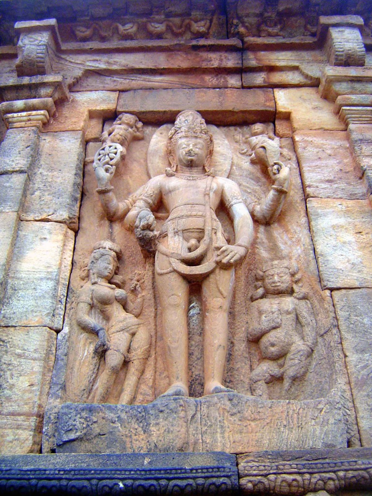 On the south side of the temple, Vishnu holds a wheel and conch. Cousens points out that it's very unusual to see a naked Vishnu, but this t