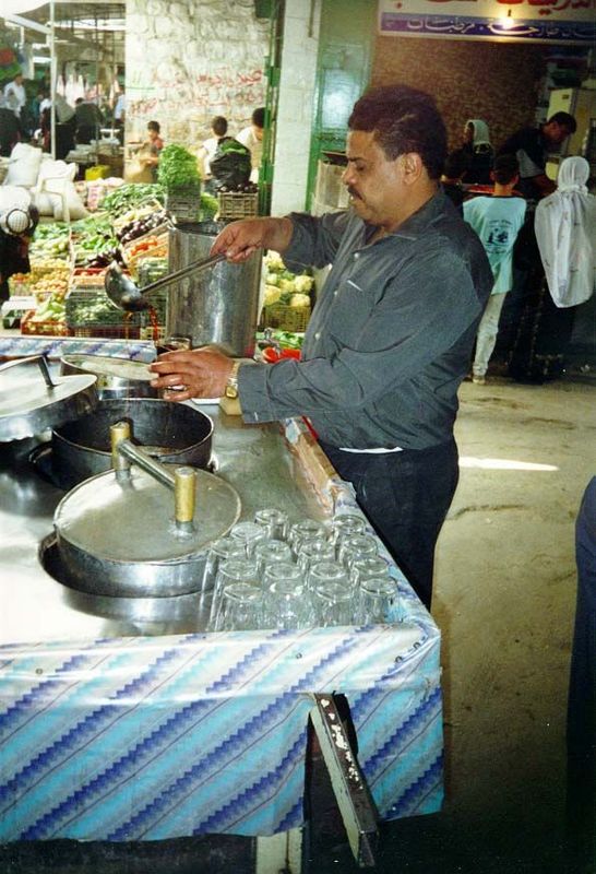 At a crossroads in the market, a vendor dilutes tamarind syrup with water and ice. The drink is sold by the glass. He lives very close, in a