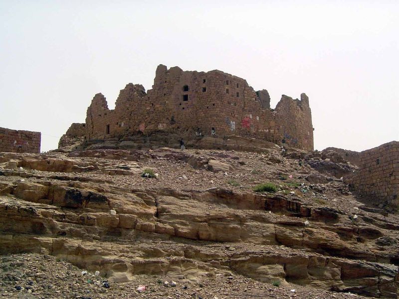 An abandoned fortress, although a couple of men sit in its shade.