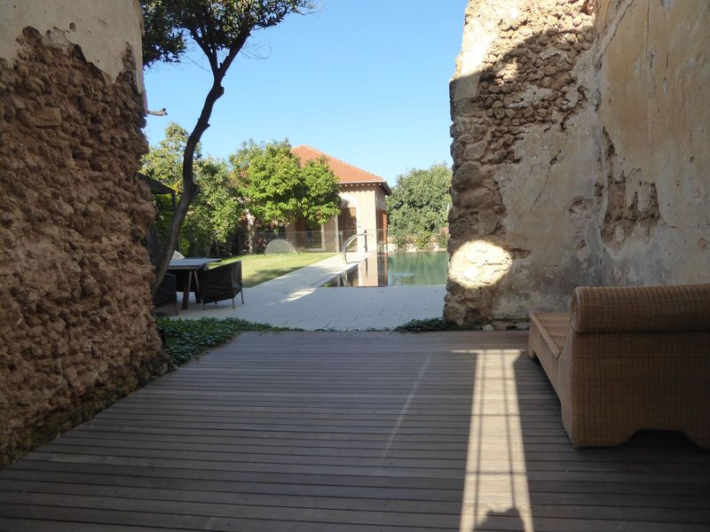 An open shutter reveals a toney nook, a pool, a bit of lawn, and a sprinkler.