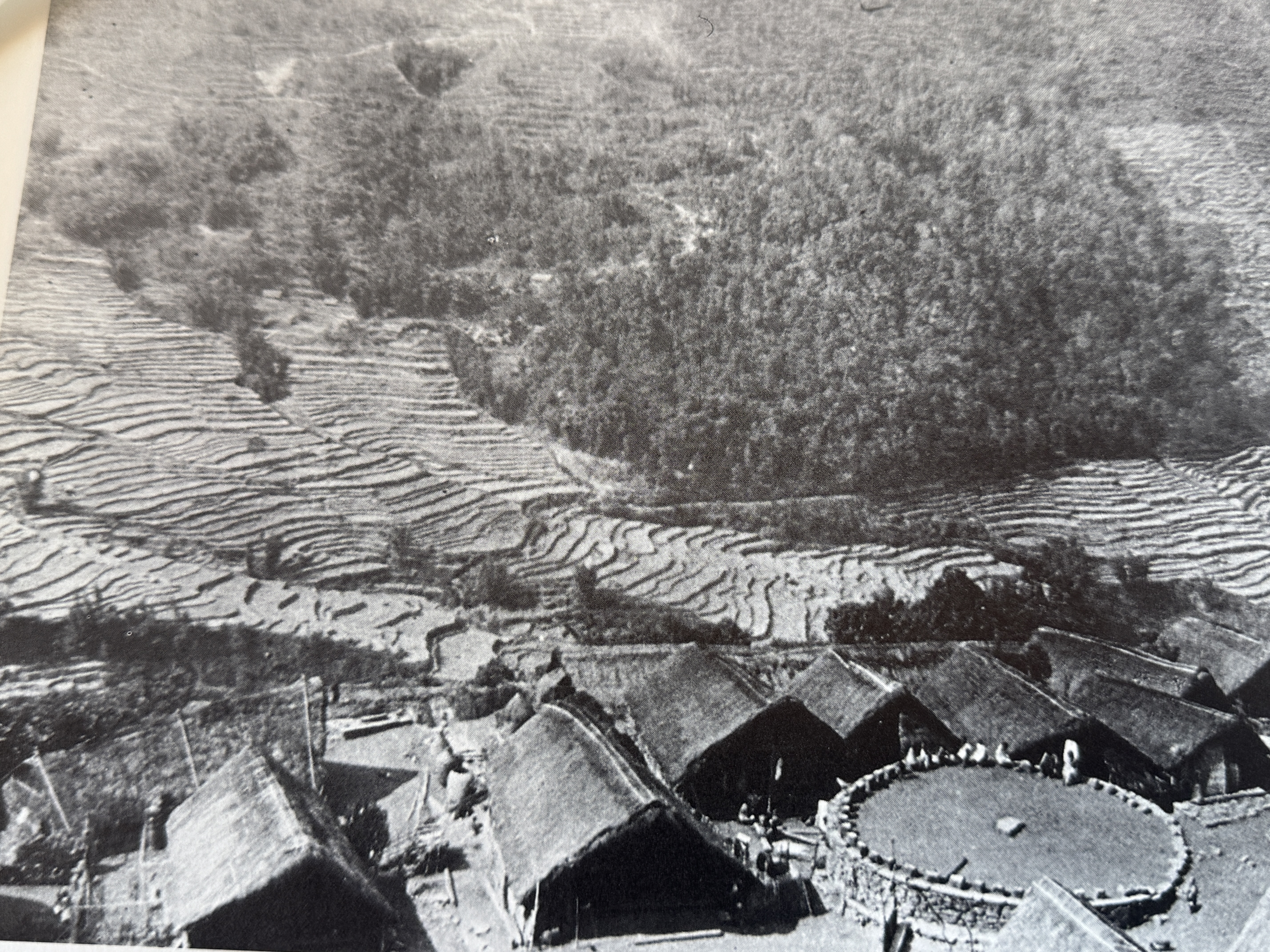 The village about 1920, with thatch-roofed houses. The circular platform is a meeting area and lookout point.  J.P. Mills, "The Assam-Burma 