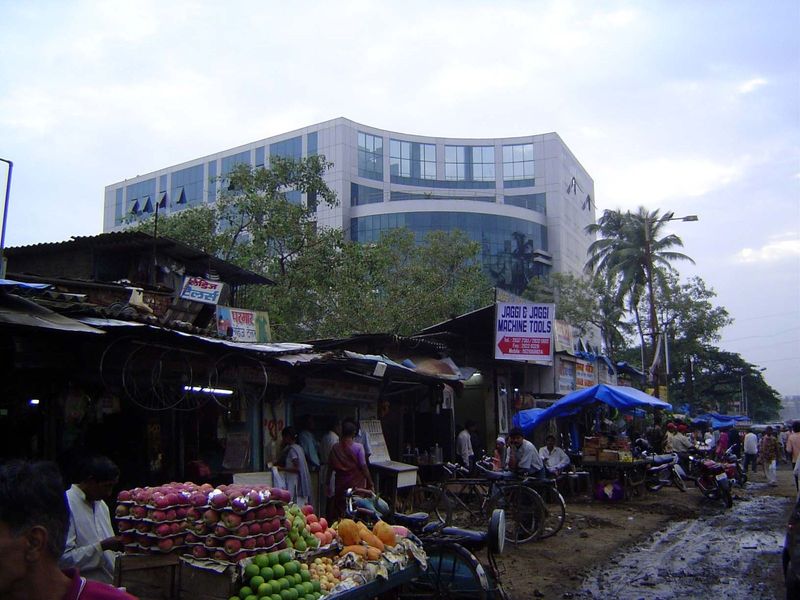 Roadside vendors and, in the background, a new building housing the Axis Bank, Electrolux India, and Skoda.