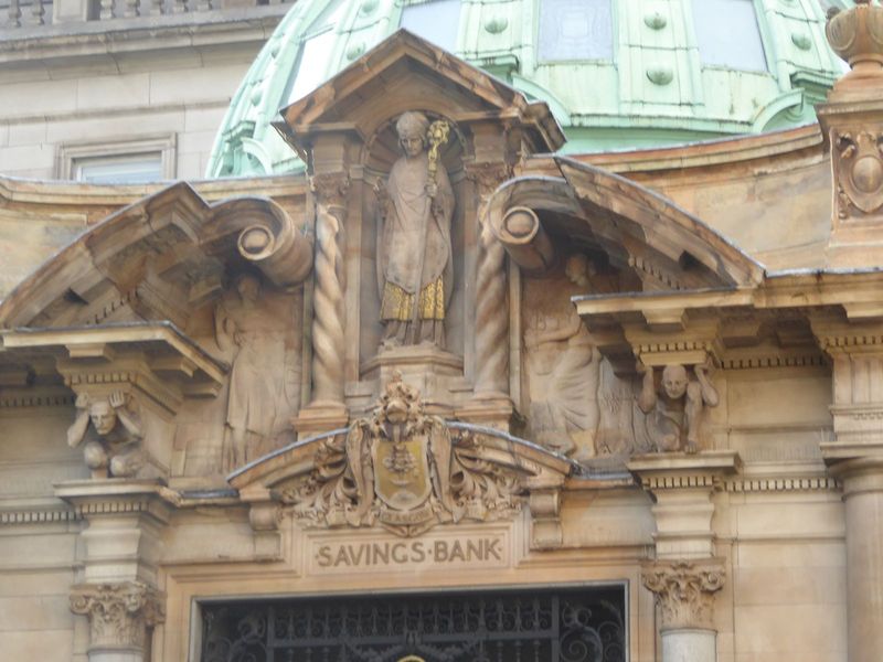 Williamson says that the banking hall's sculpture is "full of imagination but strictly subservient to the architectural forms." The figure o