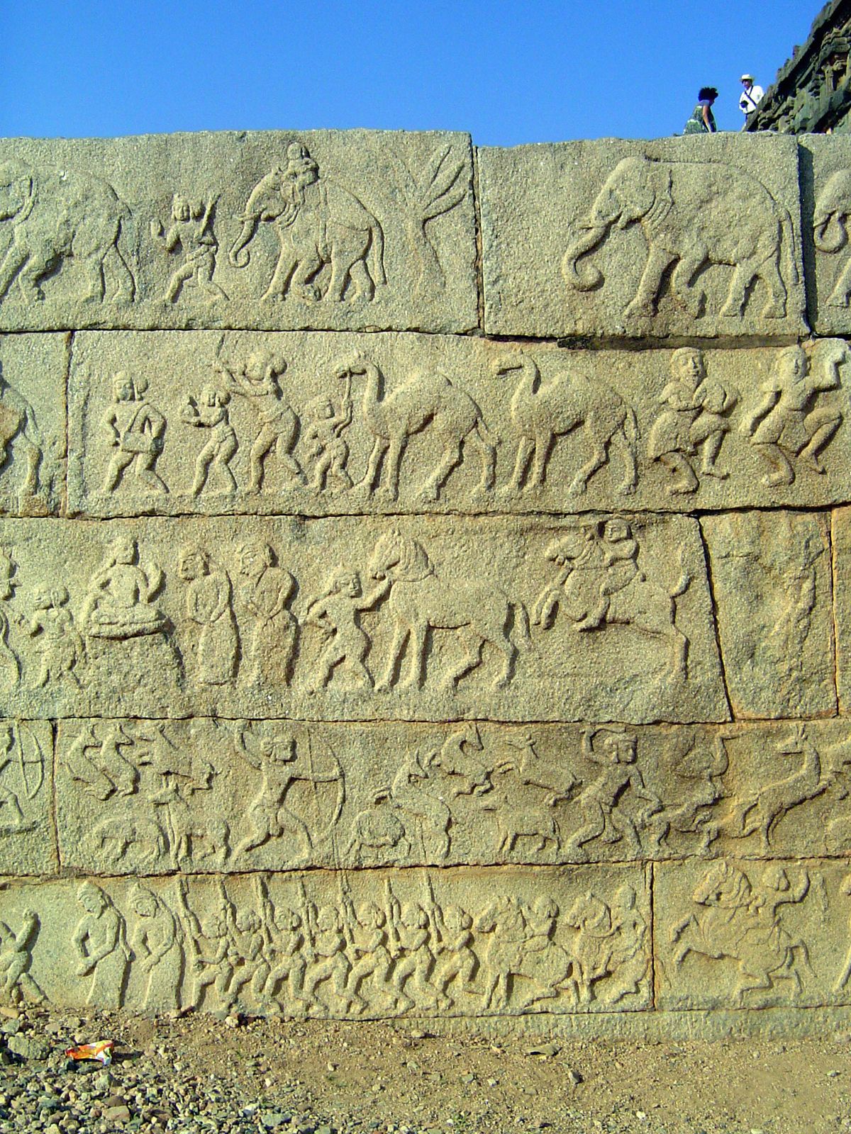 The bottom tier illustrates the king's daily life, with military drills, hunting, obeisances, and exotic entertainments with camels and fore