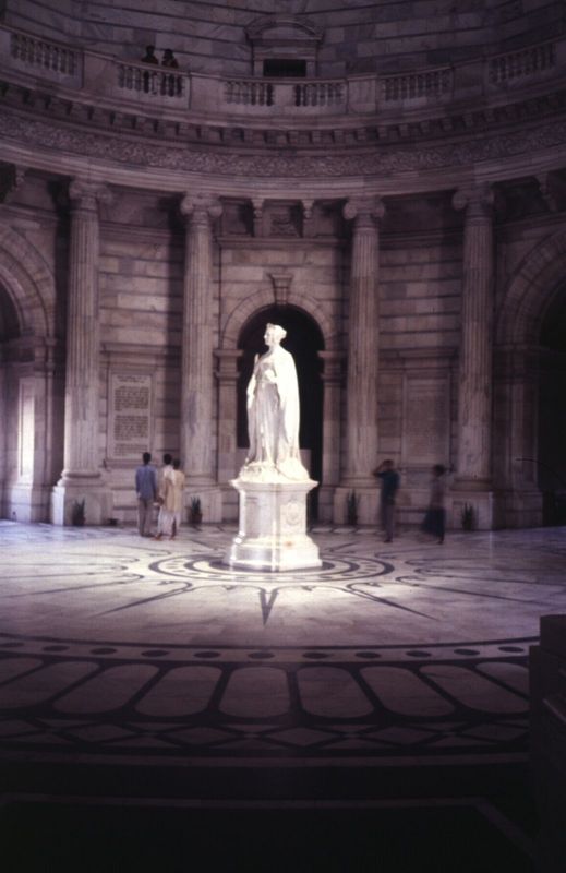 A young Victoria stands in the Queen's Hall, the central rotunda of the building. She manages to looks cool despite the heat. The building m
