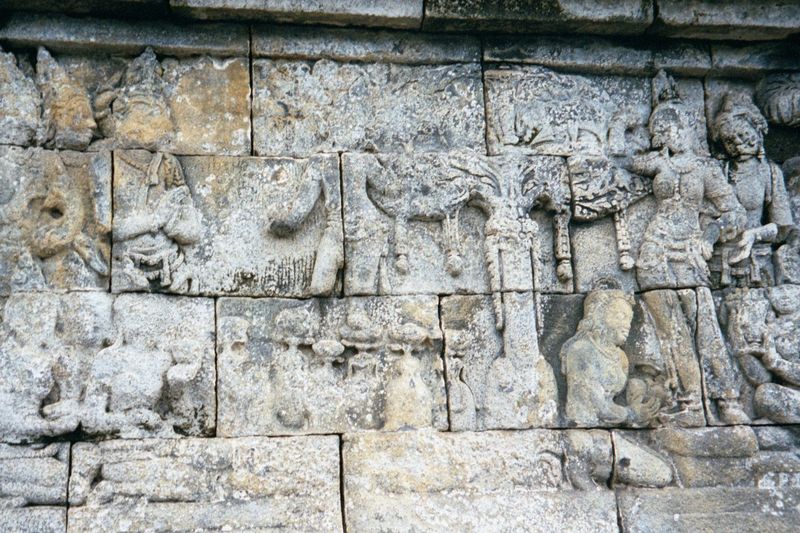 The same panel: the quite large and now defaced infant stands on lotuses, which spring up at his every step.