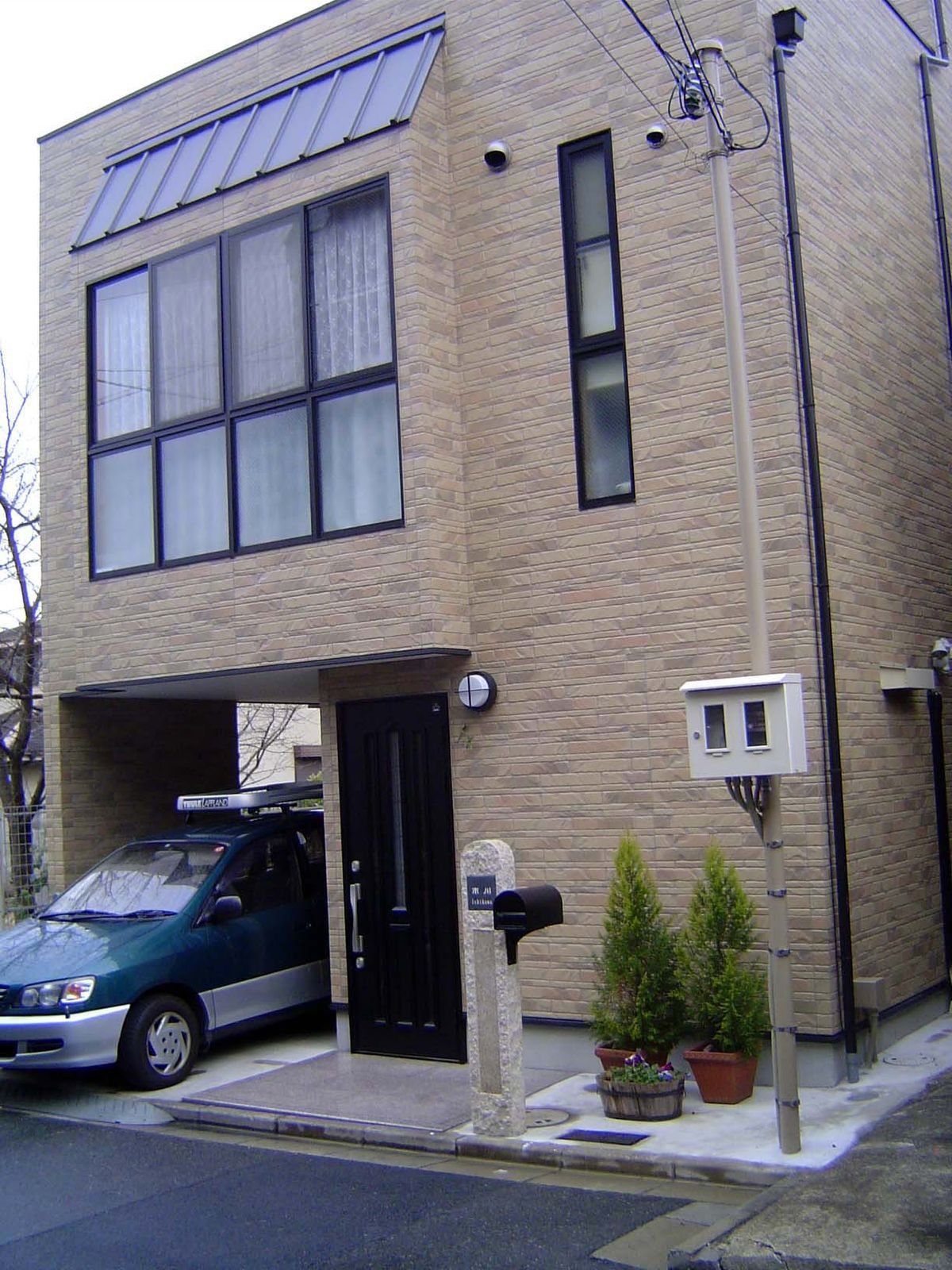 Another street, with a house that makes a sharp break from tradition, except for the stone pillar holding the mailbox.