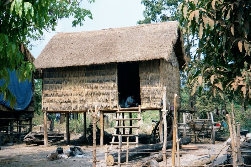 The dollars do trickle. Here, a simple house—thatch and matting on poles—of a family with wheels in the garage.