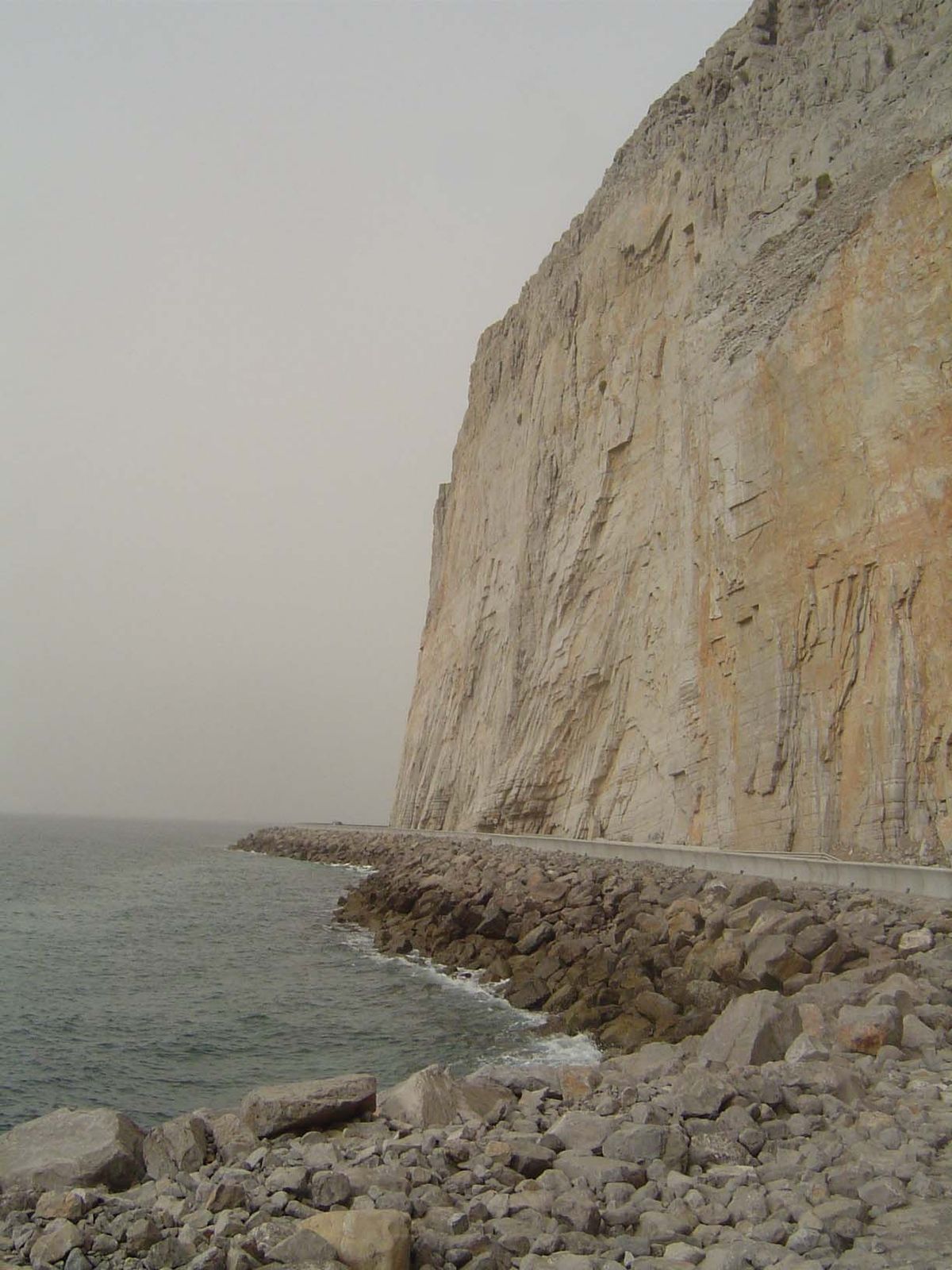 The highway runs on fill at the bottom of a cliff.