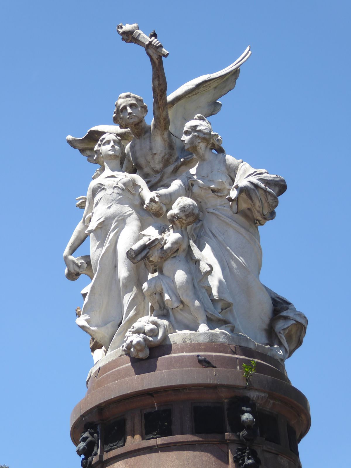 Emile Peynot created the figures, representing Argentina, France, and the guiding angel of glory. Which young woman is Argentina? Pretty eas