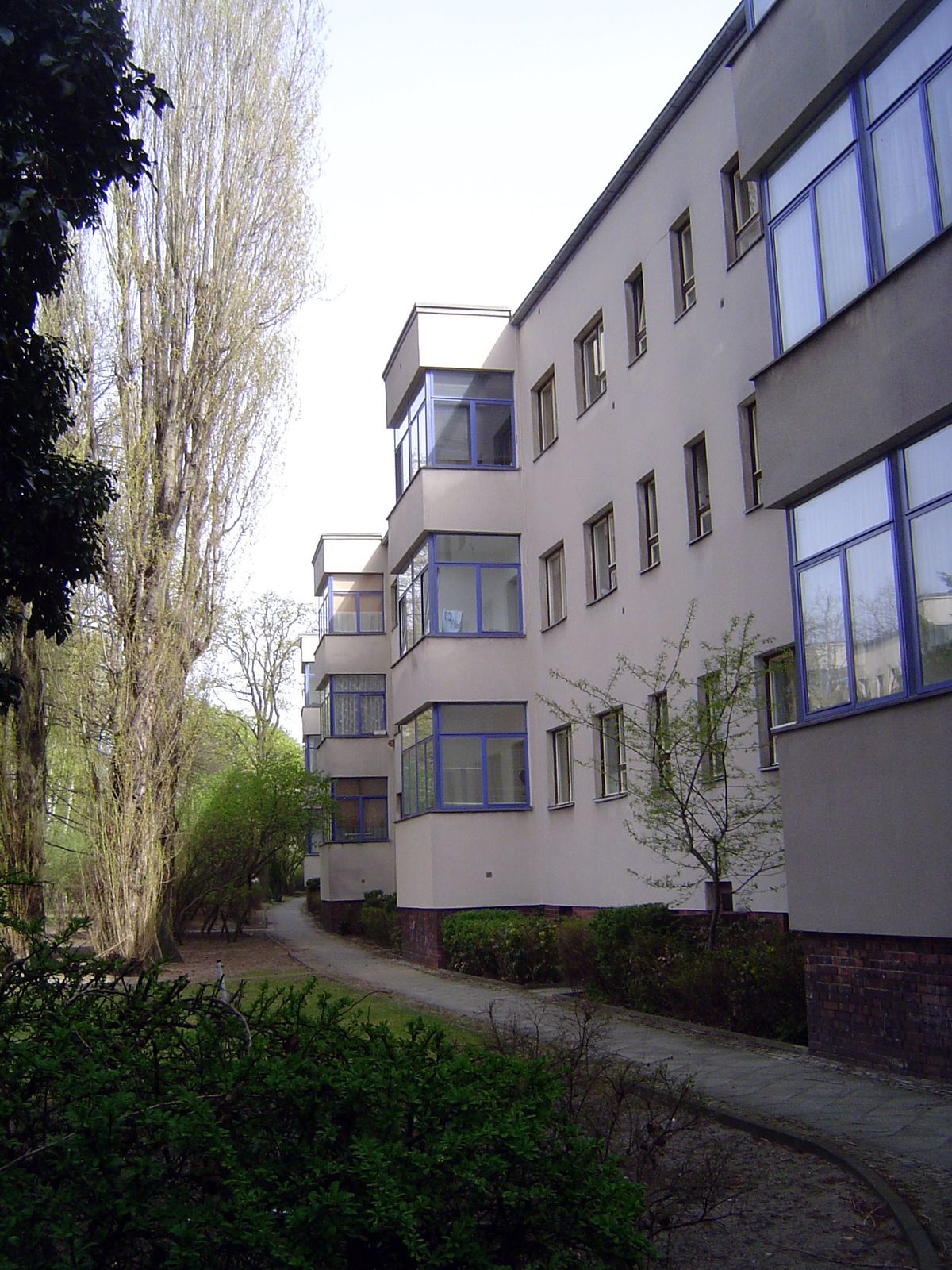 The back of the curved buildings opens on greenspace with glassed-in balconies.