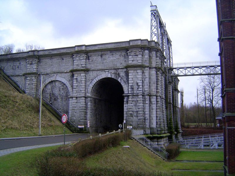 A road passes under the end of the canal, blocked by vertical gates opened when a caisson is at the top.