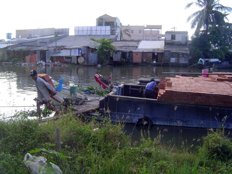 A barge loaded with brick is unloaded the hard way.