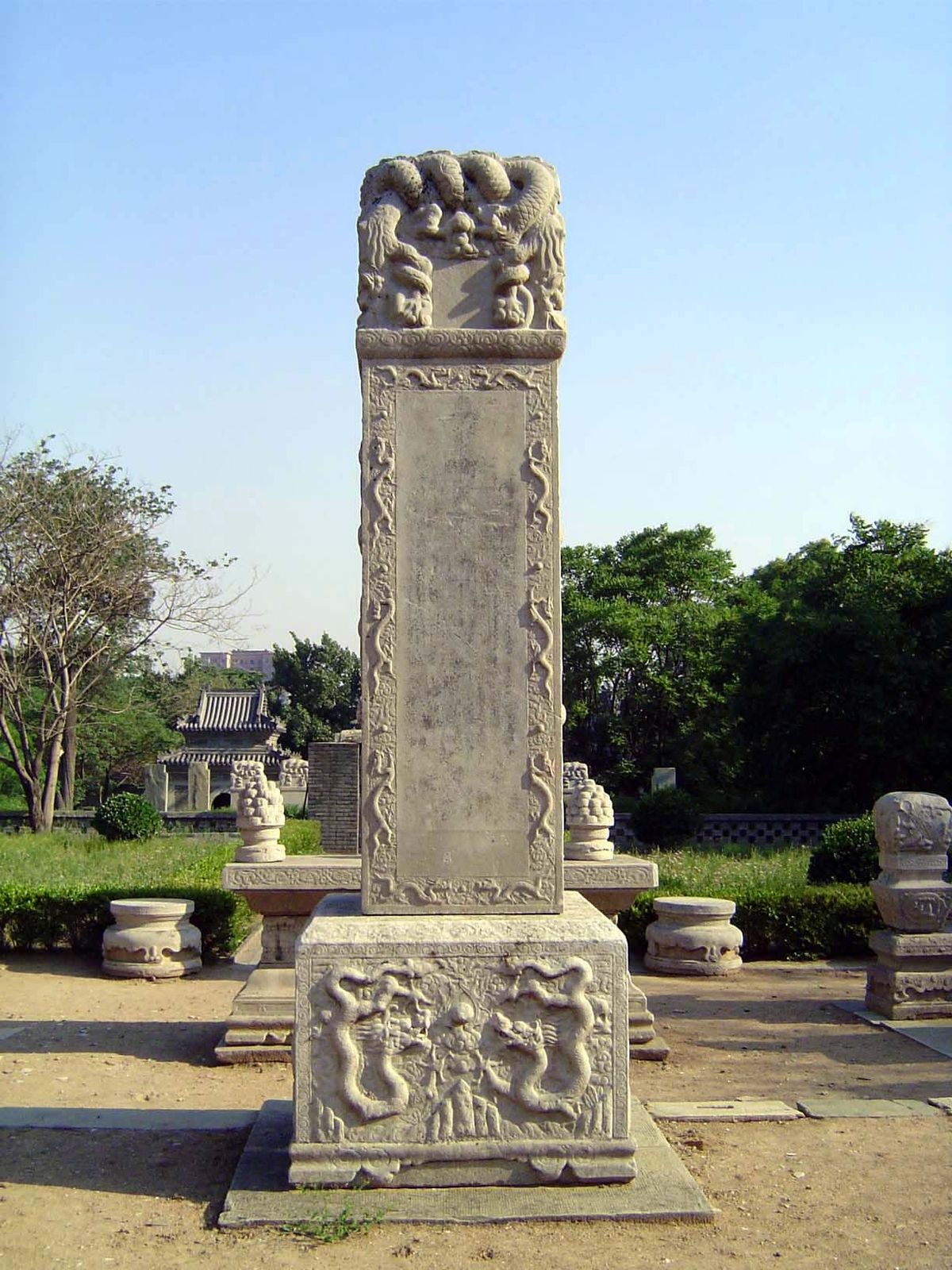 On either side of the stele but set back in front of the hedge are stone vases used in sacrifices.