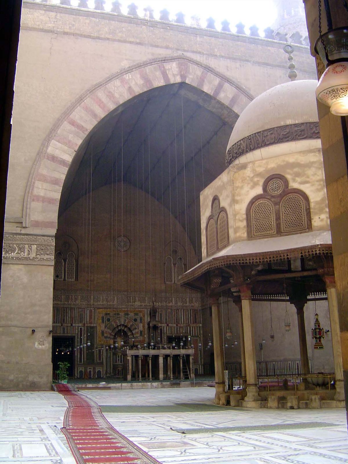 Inside, a cruciform plan with four iwans for the four schools; the polychrome marble floor is a 19th century improvement. The tomb lies thro