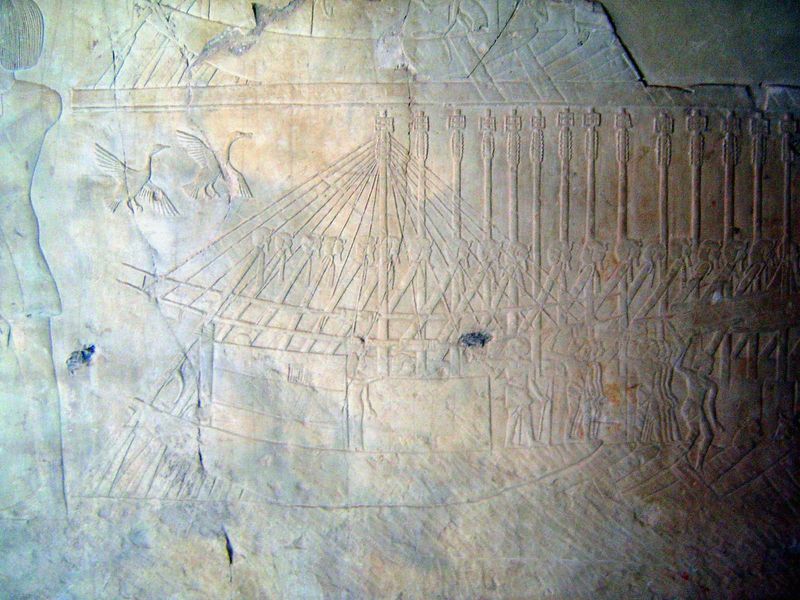 A grain-transport ship unloads at Thebes. The handles of the oars are carved with images of the king.