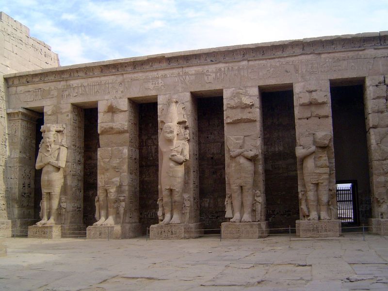 The north side of the first court has a line of Osirid columns facing the royal palace to the south. Small figures of Amun sat on the should