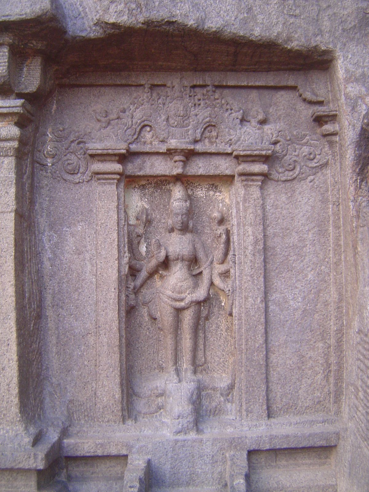 On the other hand, Durga stands impressively atop the severed head of the buffalo demon. Above her is a makara torana, a gateway, that is, i