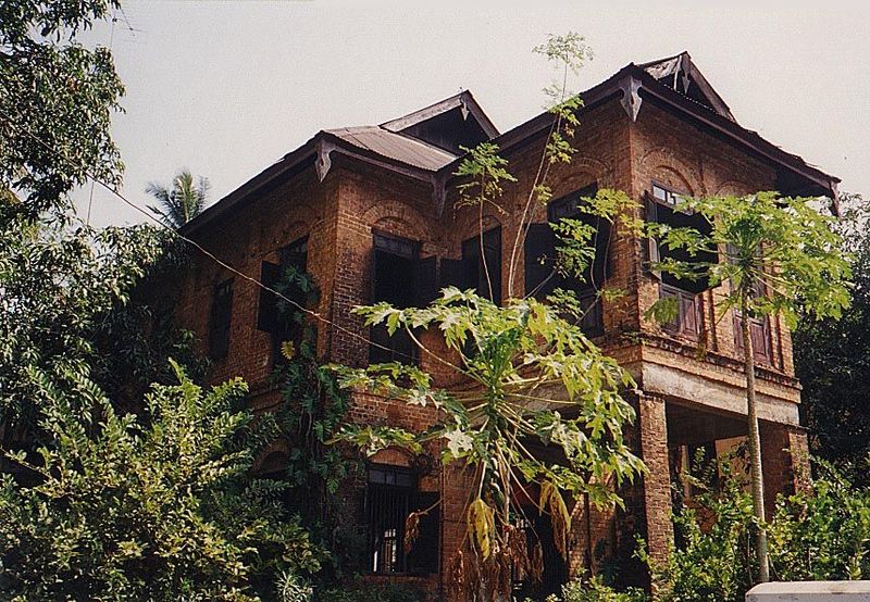Papayas grow in the front yard of an old brick house.
