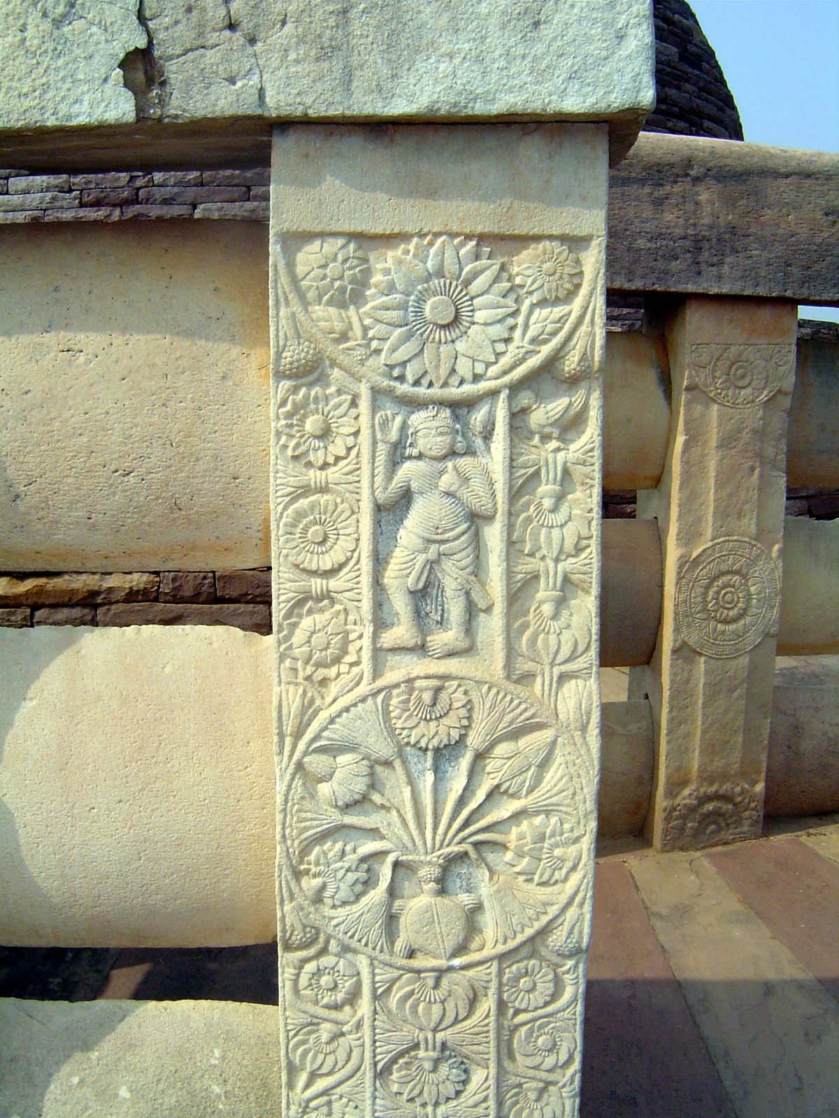 The great stupa's balustrade is devoid of ornament; here, however, the posts are covered with decoration, typically the lotus, a symbol of i