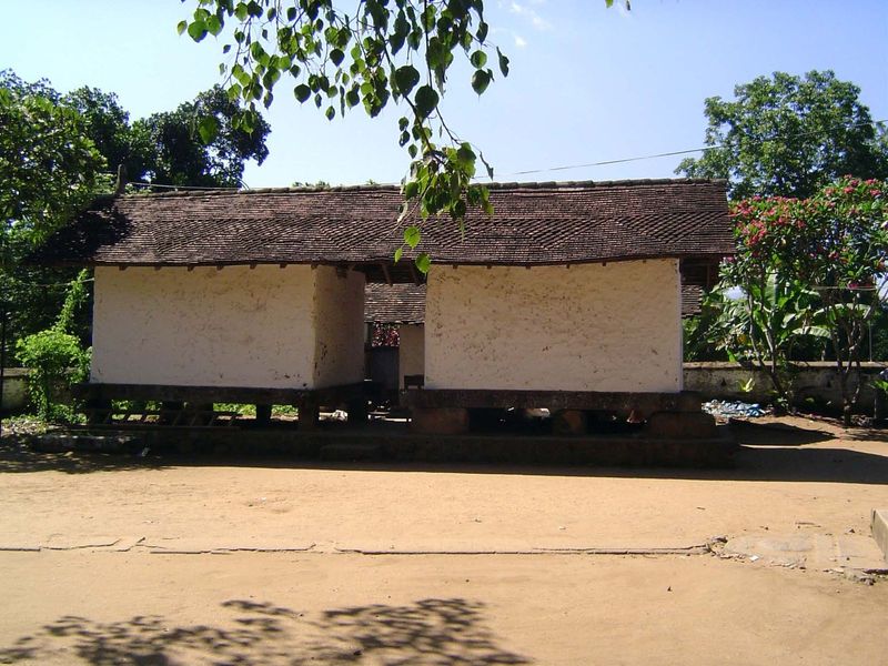 Off to the side is a bissa or rice barn. Behind the wattle-and-daub walls, stone columns support the tiled roof. There is only one door to e