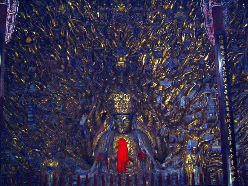 In a dark room sits the thousand-handed Avolokitesvara, Guanyin in Chinese. The story is that he was a bodhisattva who was given a dharani o