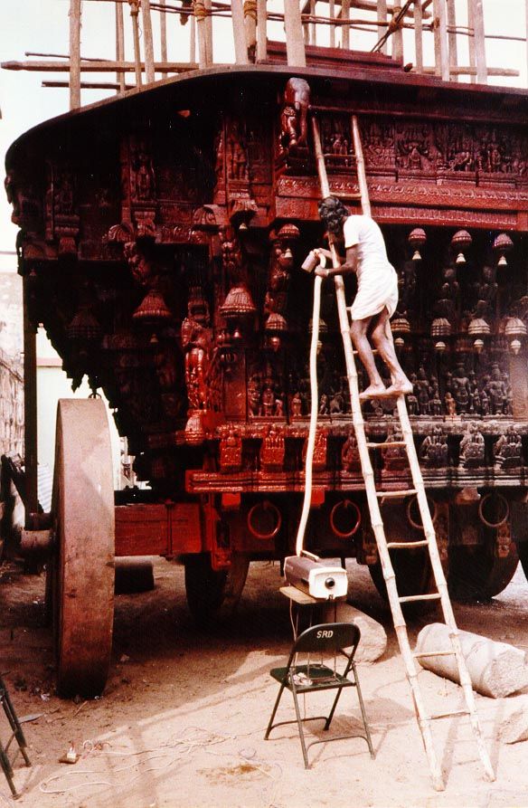 A vacuum cleaner working in reverse as a spray painter on a temple cart at Madurai, Tamil Nadu.