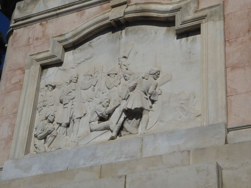 The monument carries martial images, too, like this rendering of the arrival of Spanish troops in 1724.