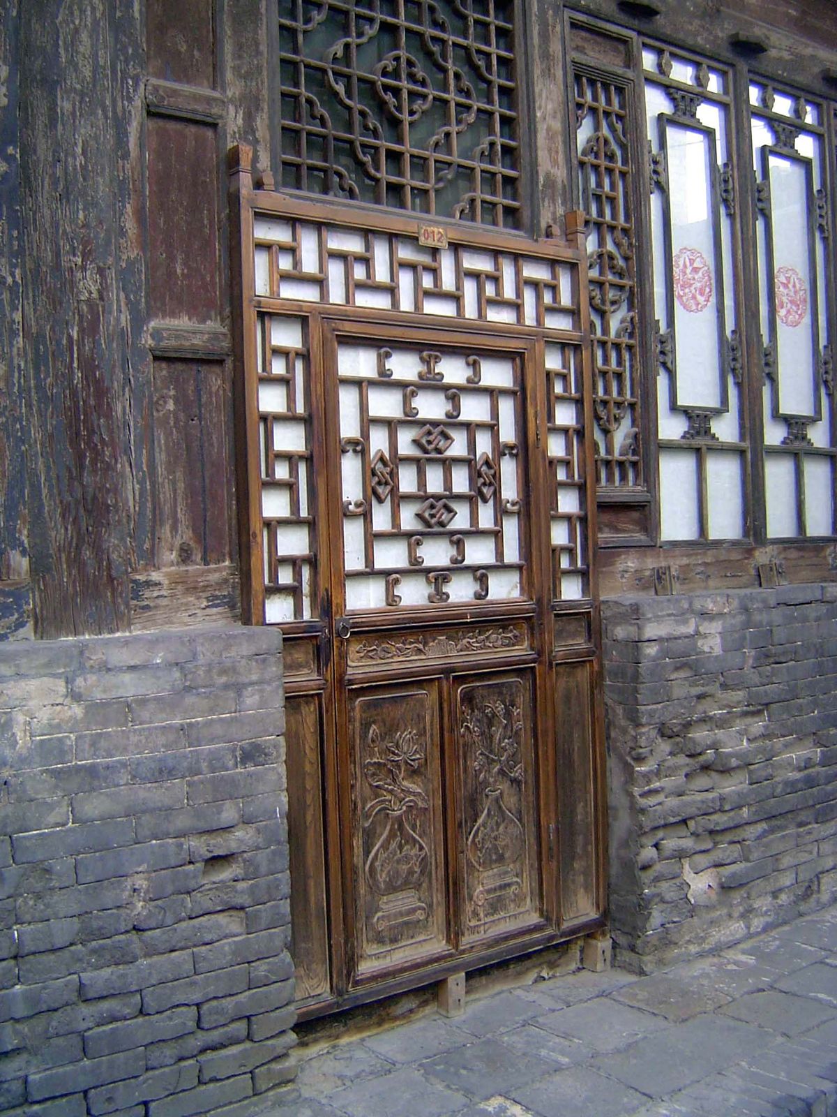 A "two-skin" door, with a thick wooden inner door and a delicate, lattice-frame outer one.
