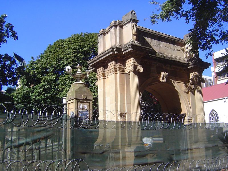 A war memorial arch from 1922 is drastically fenced off from a construction site.
