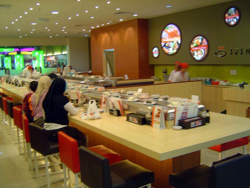 Sushi delivered by conveyor.