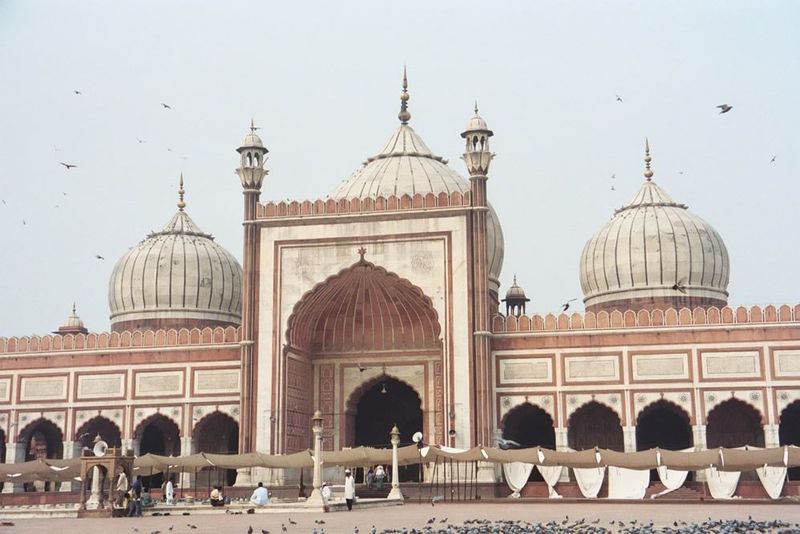 At the far side of the square is a wide but narrow prayer-hall open on three sides and capped by bulbous domes. The main arch, the iwan, lea