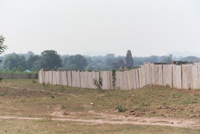 Bedrock provides material for the occasional fence. The background temple is Duladeo, a late Khajuraho temple. Khajuraho is located near the