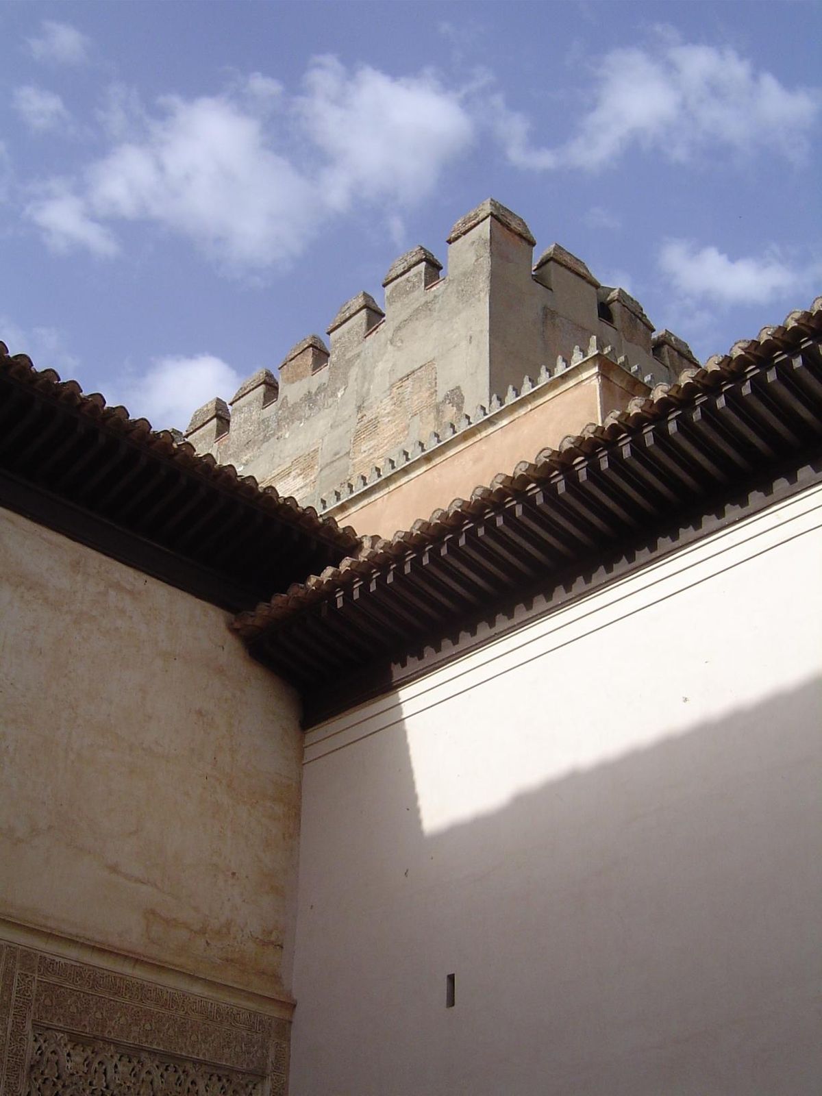 The spandrelled wall is at the lower left; the looming Tower of Comares lies off a second courtyard.