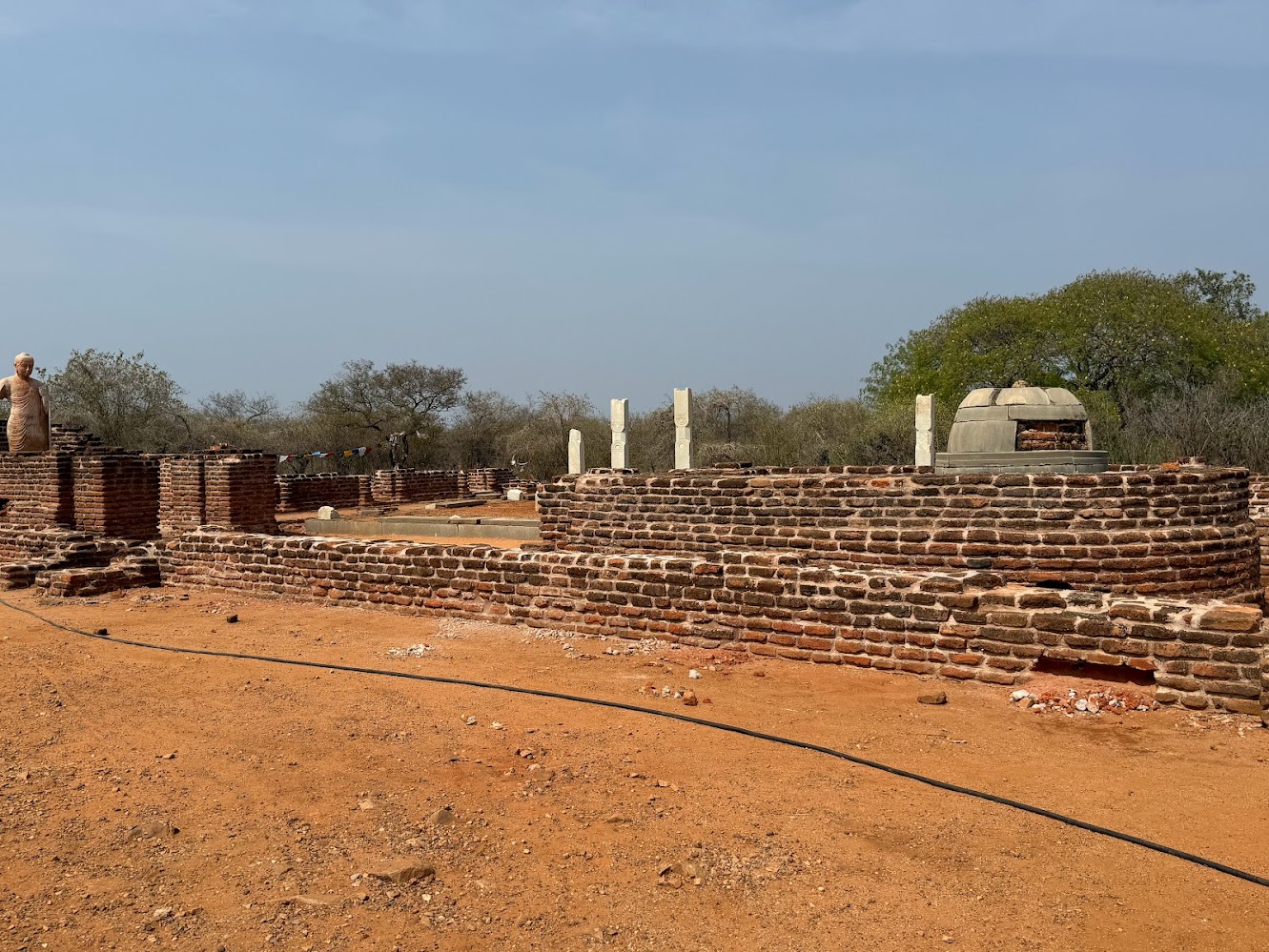 The pillars once held up the roof of a monastery.  Nearer to the camera are two prayer halls, one with a statue of the Buddha it's a replica