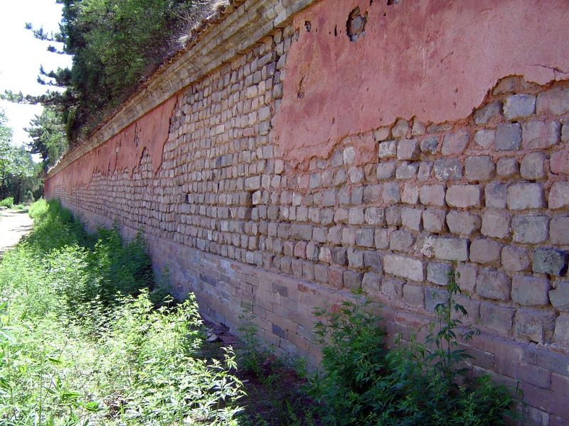 Behind the spirit tower is the forested tumulus, unexcavated and rimmed with this square wall in imperial vermilion.
