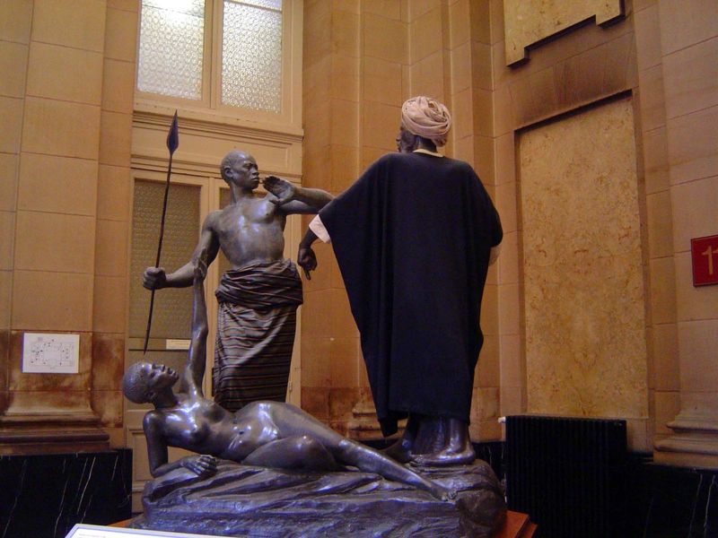 Another portrayal of slavery, this time by Charles Samuel 1882-1935: the native protects his wife against the slave-raider. The wife herself