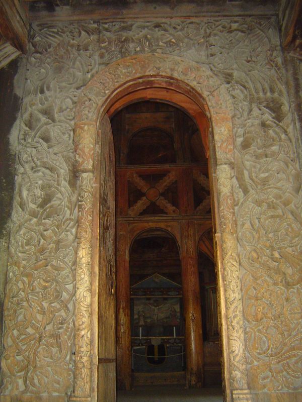 The jambs, lintel, and the columns supporting the curve of the archivolt are covered with carved vegetation and near the top of the opening 