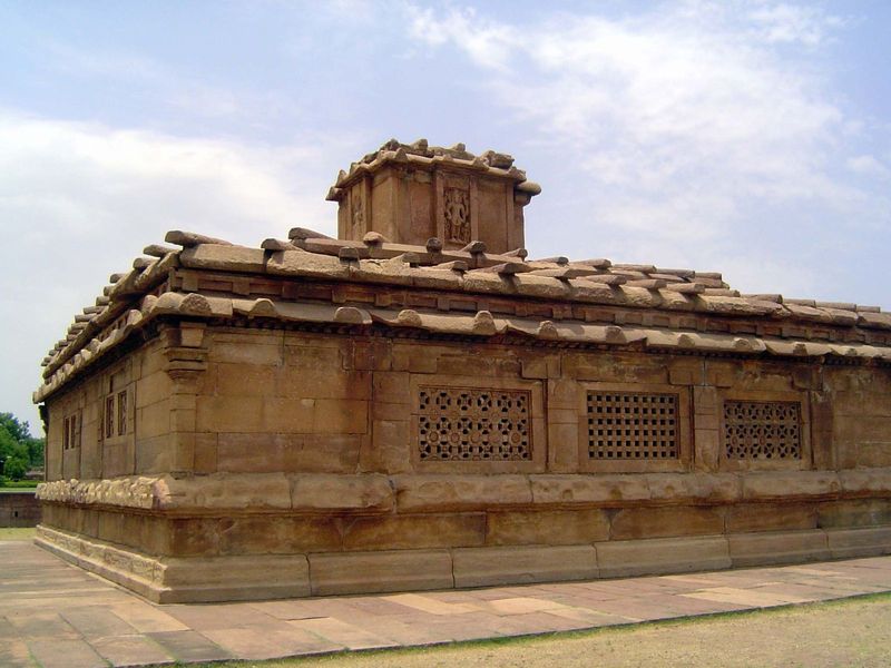 Plain exterior walls enlivened only by lattice windows. The stone columns laid across the roof may hint at the conventional practice of stab