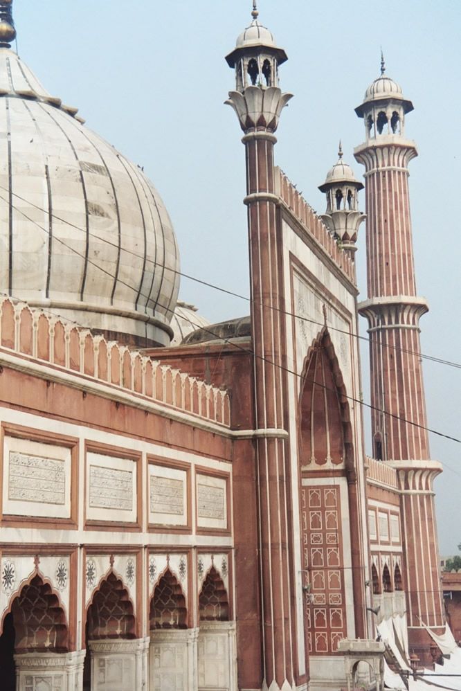 A view of the prayer hall's sandstone and white-marble exterior. The partially obscured minaret is one of a pair; its partner can be climbed