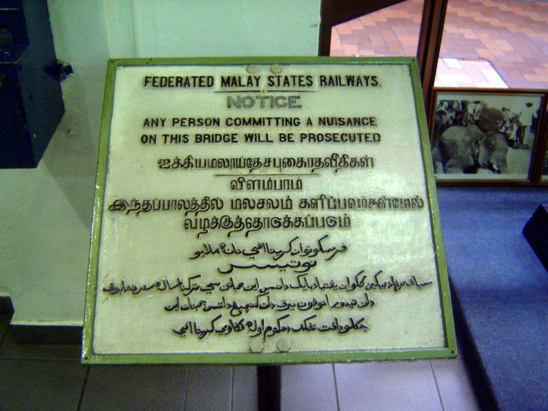 An old railroad sign in English, Tamil, and Jawi, an Arabic adaptation formerly standard for Malay.