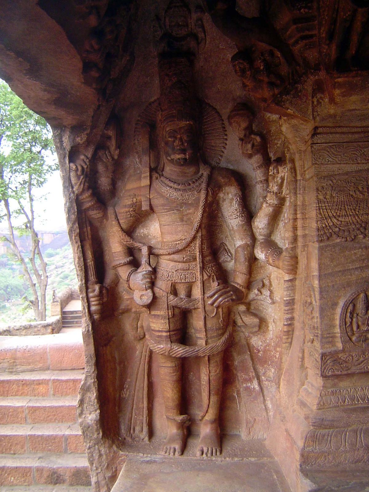 The doorway guardian is Virata-Purusha, an eight-armed Vishnu carrying on his right a wheel, arrow, mace, and sword; on his left, he carries