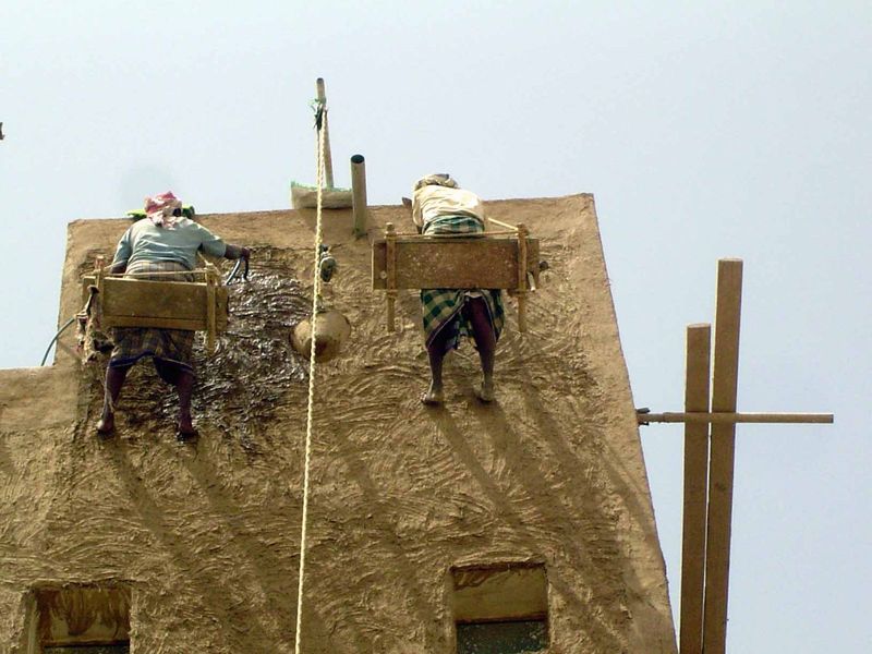 The man on the left sprinkles the surface before applying new mud.