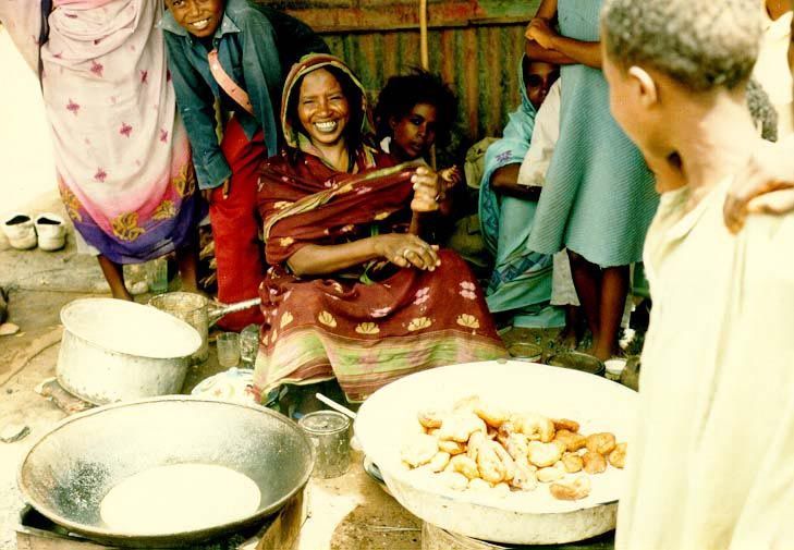 Another woman cooks and serves lunch.