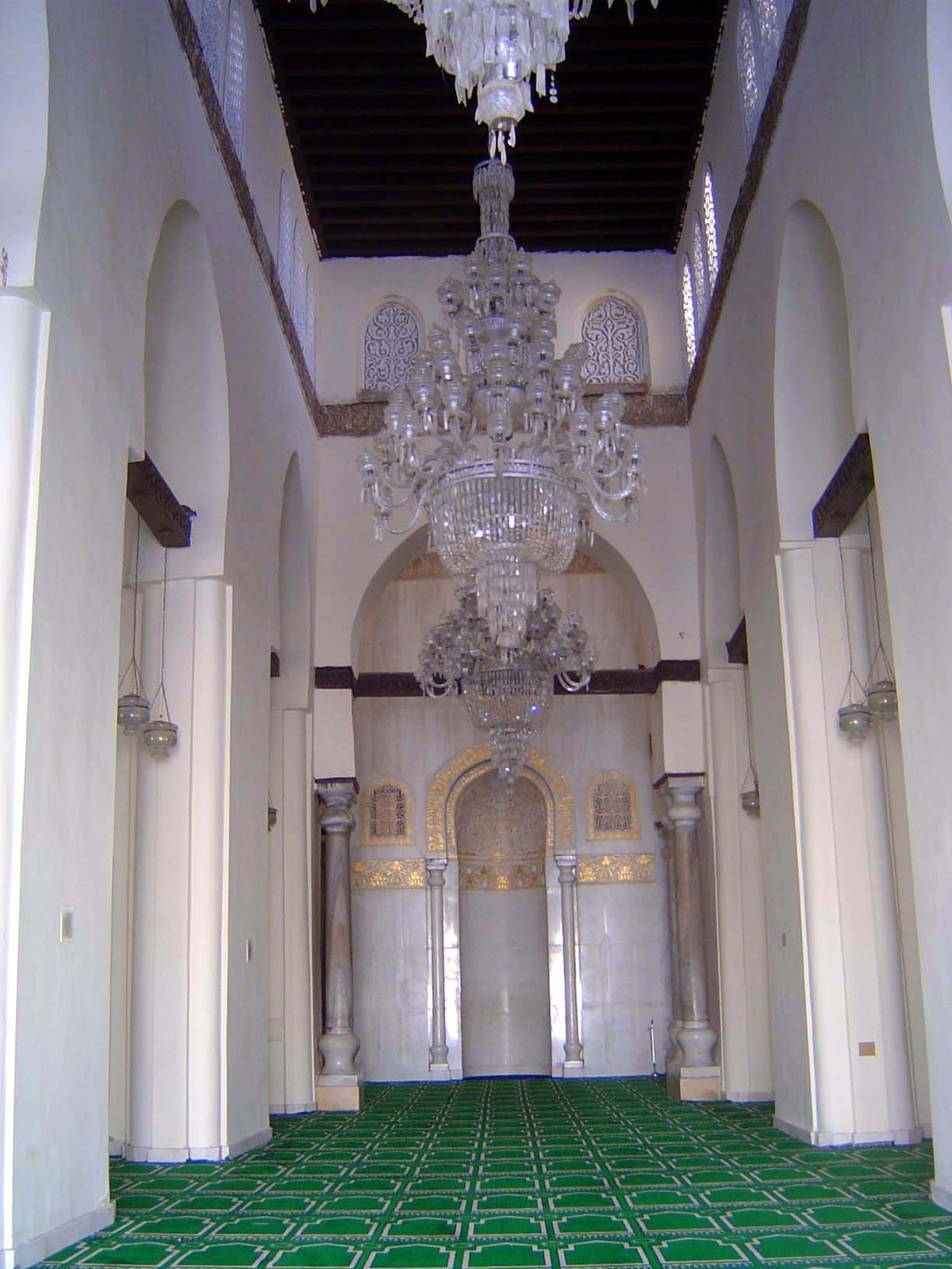 We've stepped from the bright courtyard into the arcade facing the almost institutionally sterile qibla wall.