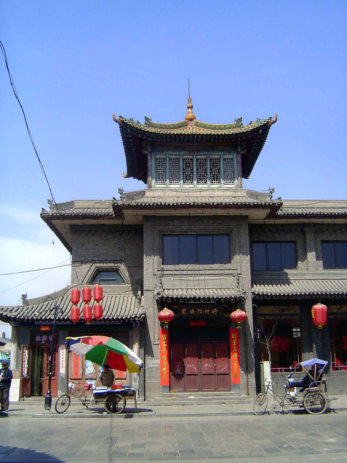 Most buildings along the street are a single story, but a few are more. This one lies at the crossing of the main east-west street with Zhan
