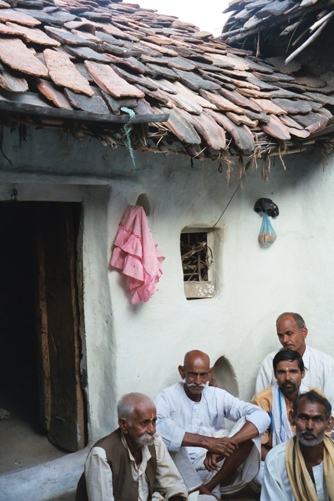 The procession passes a house in whose courtyard men have gathered.